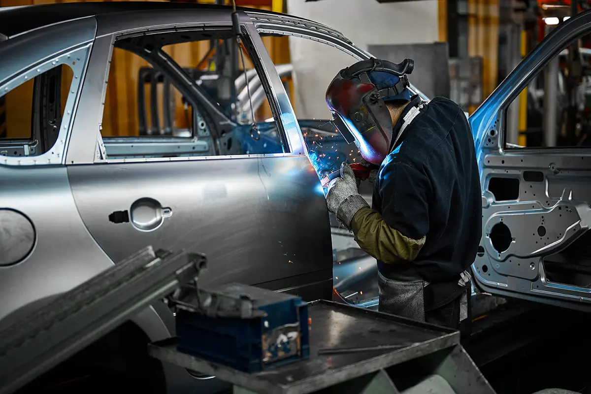 Professional auto body collision repair and welding on a silver car.