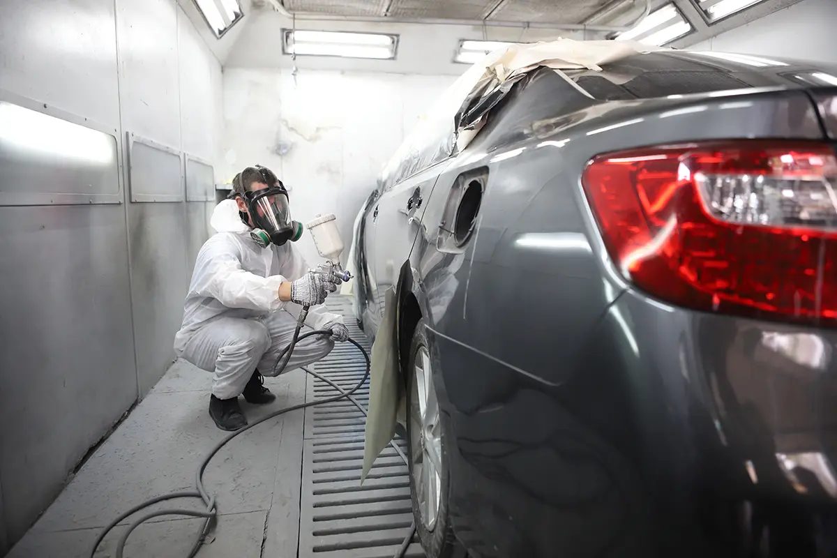 Collision repair professional painting the rear panel of a vehicle.