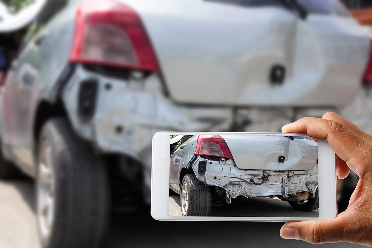 Documenting collision damage with a phone camera after an auto accident.