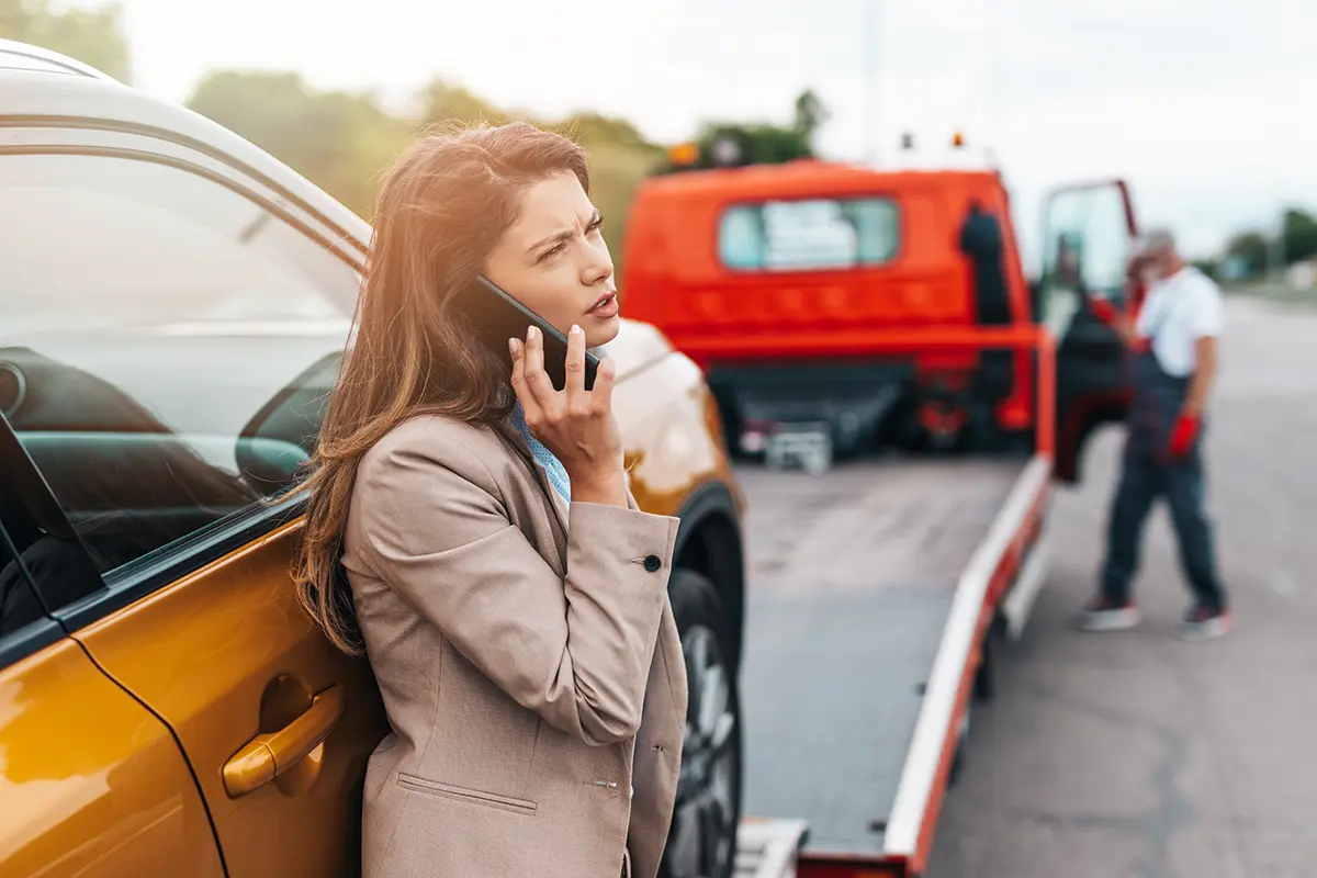 Concerned woman making a phone call after an accident to arrange vehicle transport.